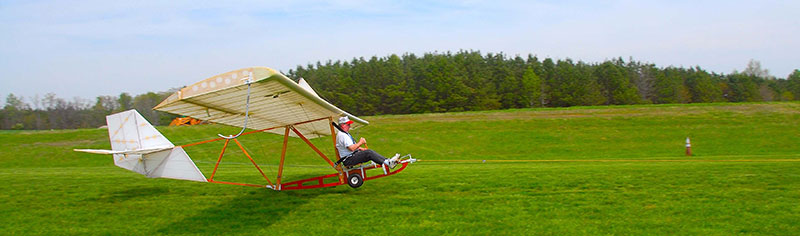 The 1929 Primary Glider Replica starts the takeoff roll with the tow-line attached to a pickup truck used for the launch.